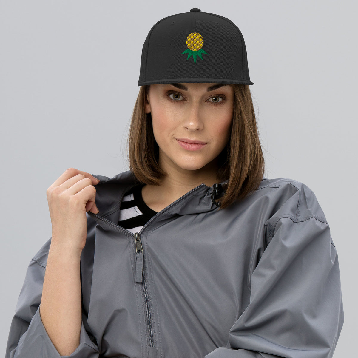 Black flat-brim snapback with embroidered upside-down pineapple, front view on model