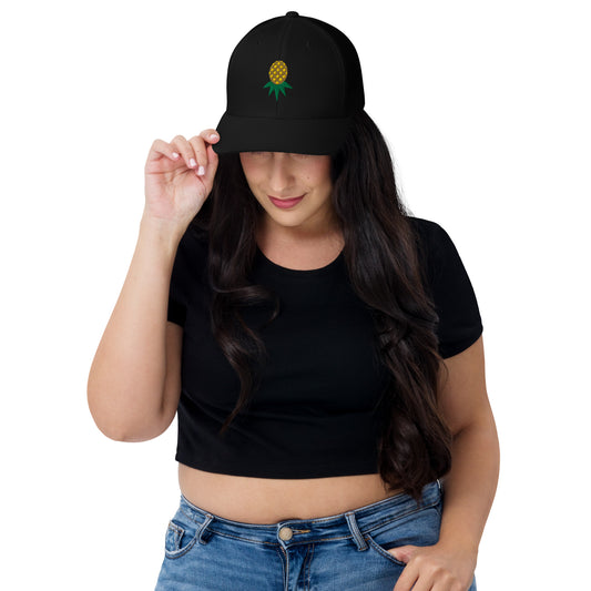 Black mesh-back trucker hat with embroidered upside-down pineapple, front view on model